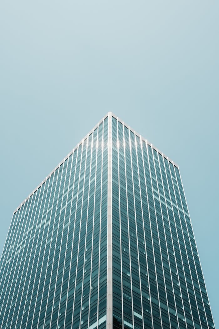 A modern skyscraper with glass facade under a clear blue sky, showcasing urban architecture.