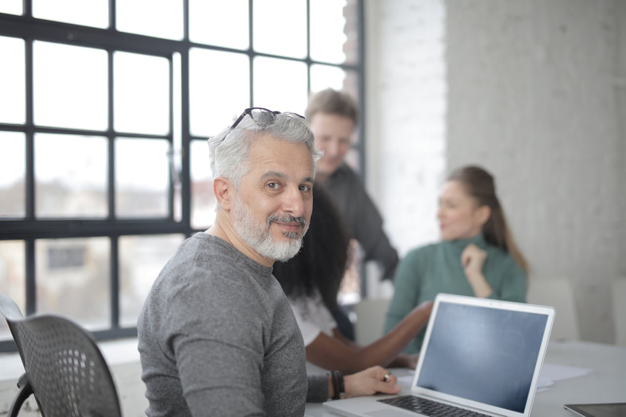 A group of diverse professionals collaborating in a bright modern office setting with laptops and natural light.