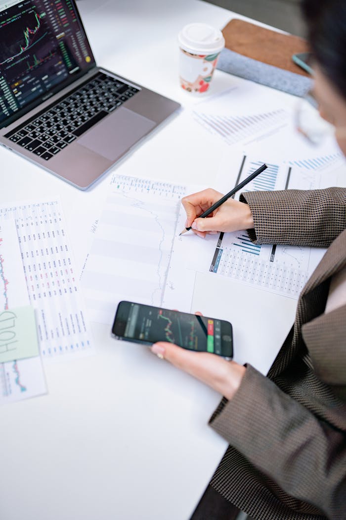why-choose-us Adult woman analyzing stock market data with laptop and smartphone in office setting.